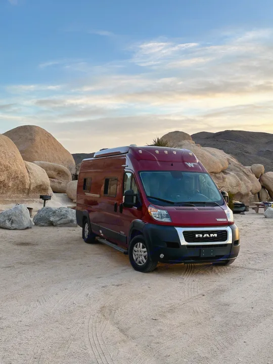 Maroon RV rental parked at a rocky desert campsite, ready for adventure under a soft evening sky.. Winnebago Solis 2022