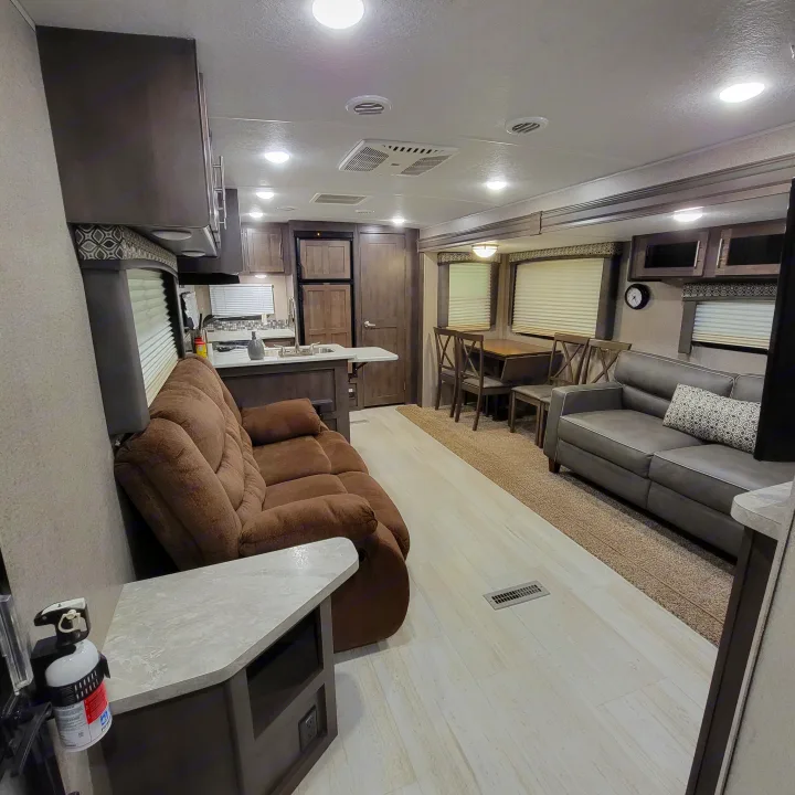 Spacious RV rental interior featuring a living area with brown and gray sofas, dining space, and a functional kitchen.. Forest River Flagstaff Super Lite 2019