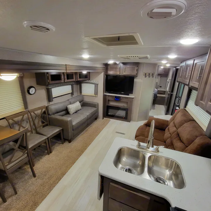 Modern RV rental interior: lounge sofa, dining chairs, kitchen, TV, and fireplace. Comfortable living on the road.. Forest River Flagstaff Super Lite 2019