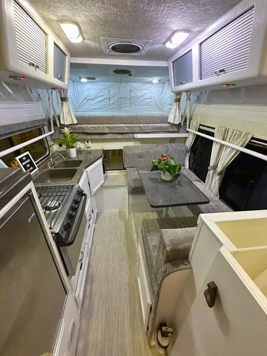 Cozy RV rental interior: kitchen, dinette, and pop-top bed. Perfect for mobile living and travel adventures.. Hallmark Everest 2011