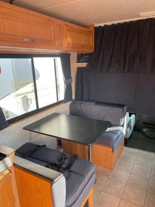 Cozy rv rental interior with dinette, overhead cabinets, and seating area with seatbelts. Perfect for travel!. Four Winds Majestic 2006