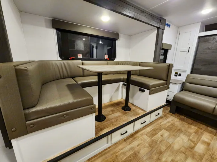Modern RV dinette features U-shaped seating, table, & under-bench storage. Ideal for your RV rental.. Keystone RV Hideout 2023