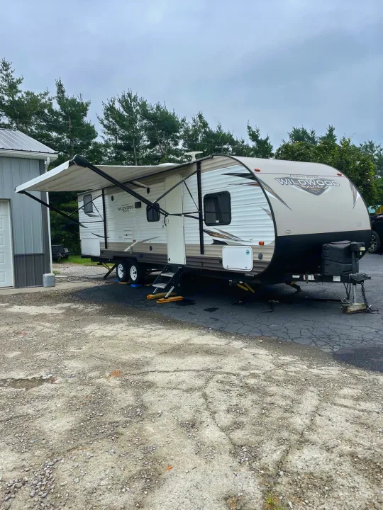 A white and tan Forest River Wildwood X-Lite travel trailer with awning extended, ready for your RV rental.. Forest River Wildwood X-Lite 2019