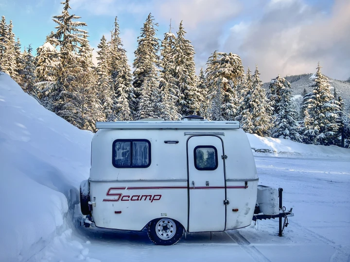 Winter RV rental: A Scamp camper parked in deep snow by snow-covered pines, mountains. Perfect for winter camping.. Scamp Scamp Trailer 2007