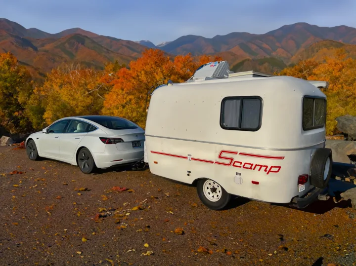 White Tesla towing a white Scamp RV rental through vibrant autumn mountains.. Scamp Scamp Trailer 2007
