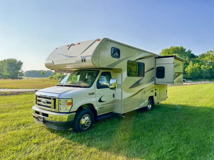 Spacious Class C RV rental parked on a sunny green field, perfect for your next outdoor adventure.. Winnebago Minnie Winnie 2021