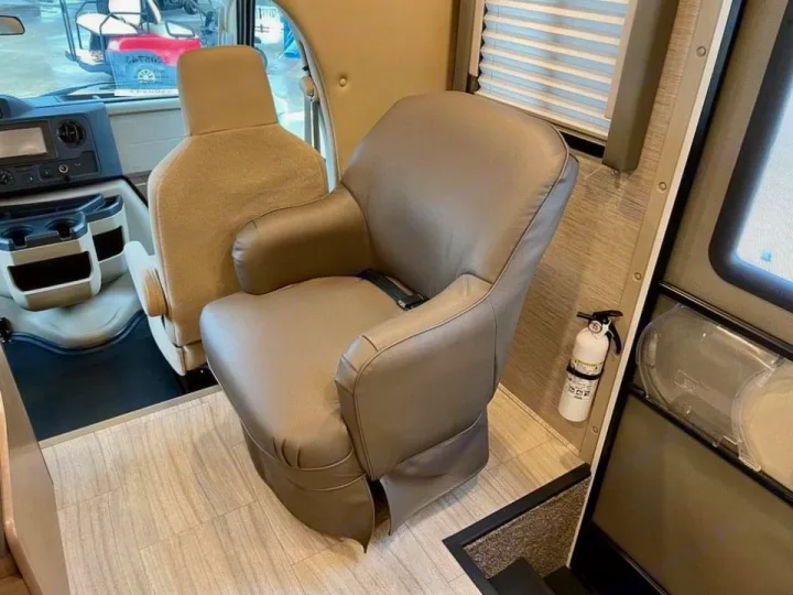 Comfortable RV rental interior showing a swiveling captain's chair, dashboard, and fire extinguisher for safety.. Thor Coleman 2022