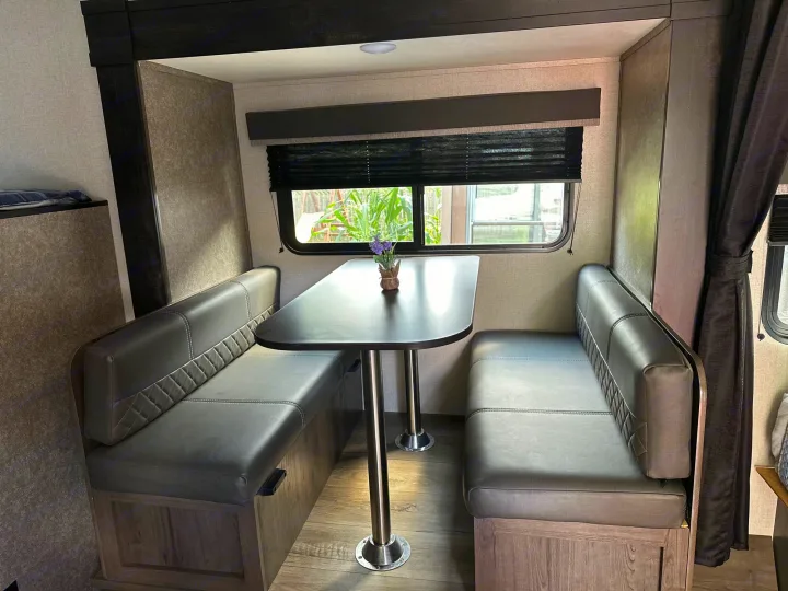 RV rental dinette: comfy dark gray quilted benches & table set inside a clean, well-lit travel trailer.. Starcraft Autumn Ridge Mini 180 2021