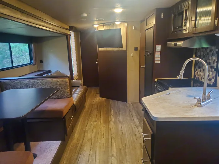 An rv rental's inviting interior: kitchen, dining, and lounge area with wood floors.. Forest River Cherokee Grey Wolf 2017