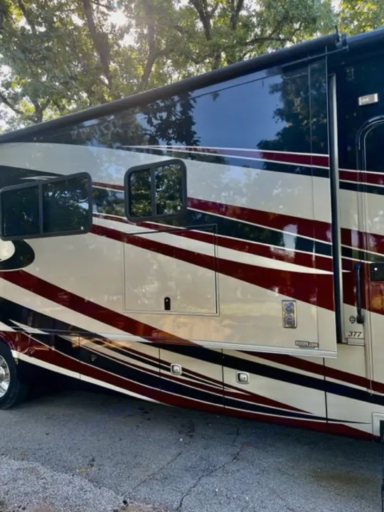 Luxury rv rental, sleek with black, white, and maroon stripes, showing large windows & storage bays, parked outdoors.. Georgetown XL 2013