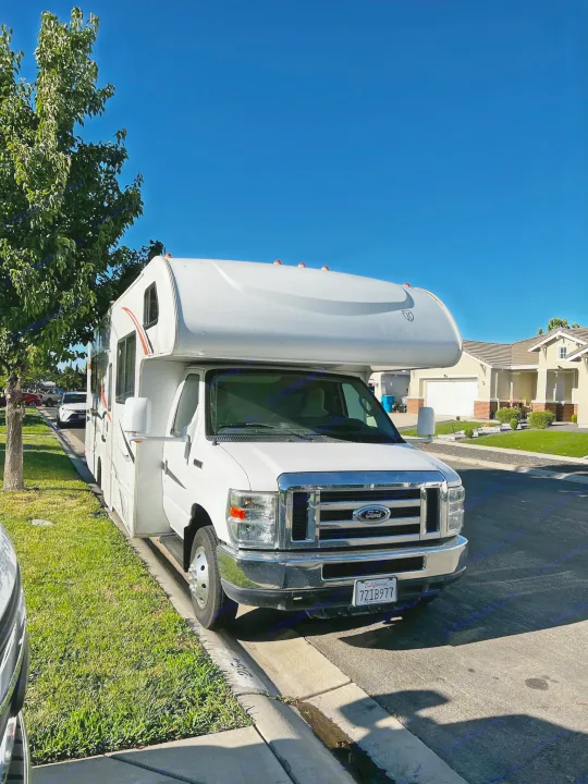 White Class C rv rental motorhome parked curb-side on a sunny residential street.. Thor Majestic 2012