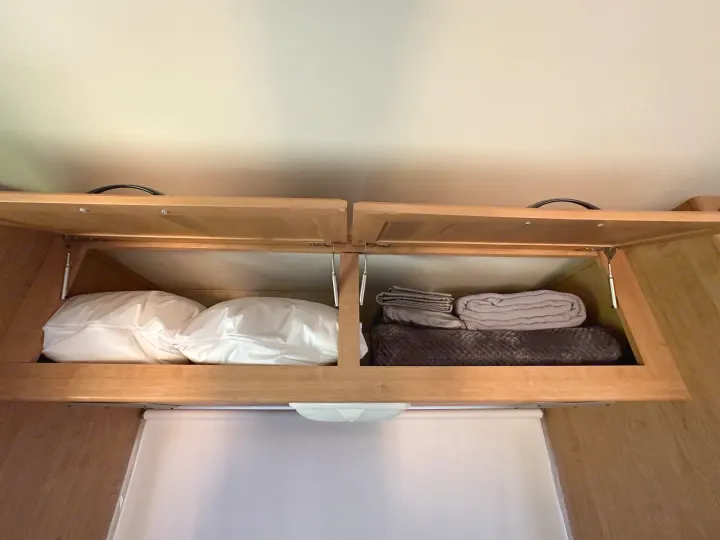 RV rental overhead storage: two cabinets filled with cozy pillows, blankets, and linens for a comfortable stay.. Thor Majestic 2012