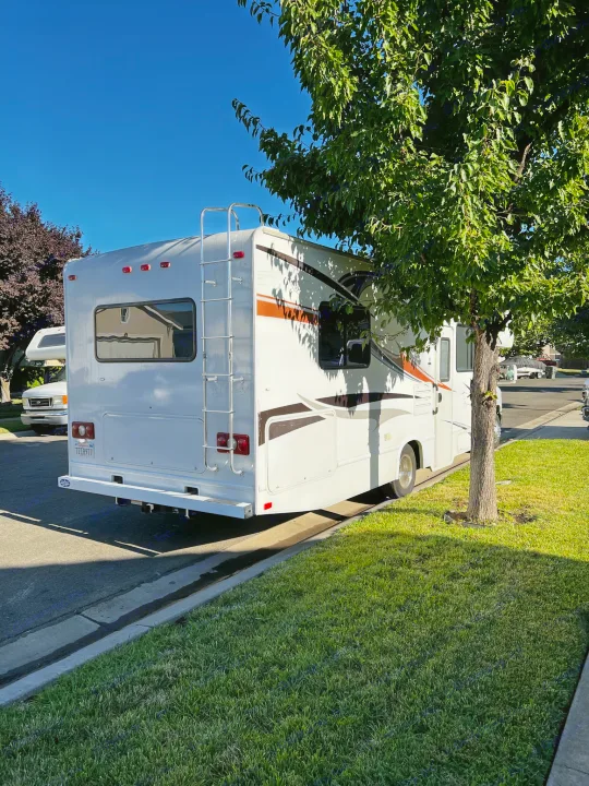 White RV rental parked on a sunny residential street with green grass. Perfect for your next travel adventure.. Thor Majestic 2012