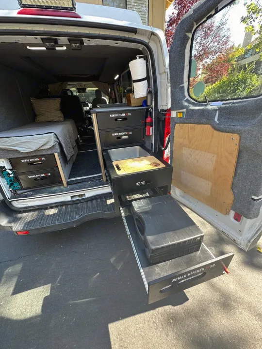 This RV rental shows a clever pull-out Nomad Kitchen Co. setup with sink, stove space, and bed for van life adventures.. Ford Transit 2016