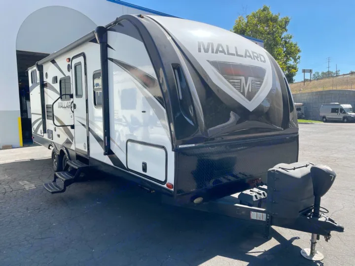 A modern white and black Mallard travel trailer, a great option for an RV rental. Parked outdoors on a sunny day.. Heartland RVs Mallard 2018
