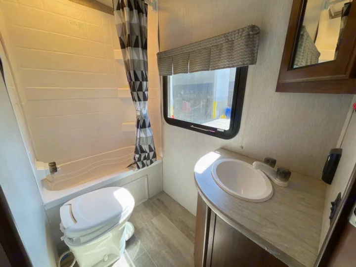 RV rental bathroom featuring a white shower/tub, toilet, and sink vanity, designed for comfortable travel.. Heartland RVs Mallard 2018