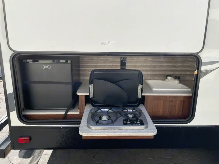 RV rental outdoor kitchen featuring a mini-fridge, two-burner stove, and sink for convenient camping.. Heartland RVs Mallard 2018