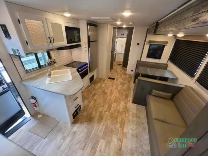 Explore this RV rental's modern interior, featuring a kitchen, dinette, and living area with wood-look floors.. Keystone Hideout 2022