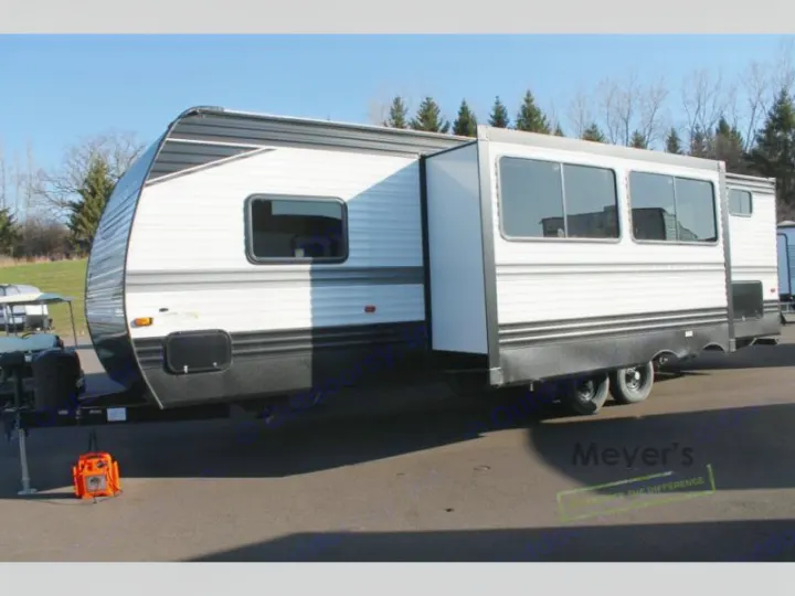 White and black travel trailer with an extended slide-out, ideal for rv rental, parked on an outdoor lot.. Keystone Hideout 2022