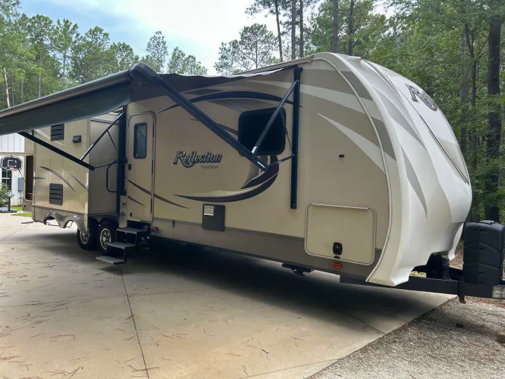 Spacious Grand Design Reflection fifth wheel RV for rv rental, parked on a concrete drive with awning extended near trees.. Grand Design Reflection 2015