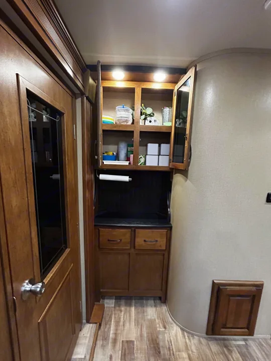 RV rental interior: functional wood cabinetry with open shelves, drawers, and paper towel holder, showcasing compact storage.. Grand Design Reflection 2015