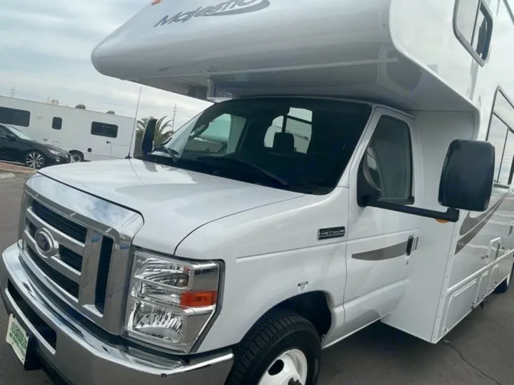 Front-side view of a white Ford Class C RV, ideal for an rv rental. This motorhome is parked outdoors.. Thor Majestic 2018