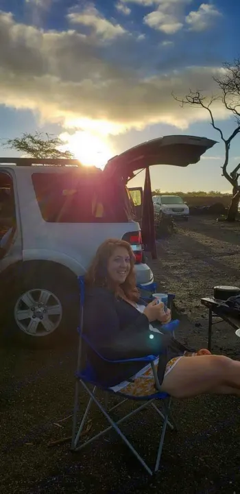 Smiling woman relaxes by her SUV at sunset. This outdoor setup highlights fun travel options like an RV rental.. Xplorer Explorer 2007
