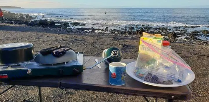A portable camp stove with pots and a table are set up on a rocky beach by the ocean. Perfect RV rental spot for outdoor cooking.. Xplorer Explorer 2007