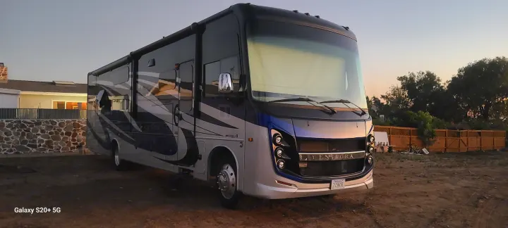 Sleek, two-toned Integra RV gleaming at dusk while parked on a dirt lot, ideal for an RV rental adventure.. Entegra Coach Vision XL 2020