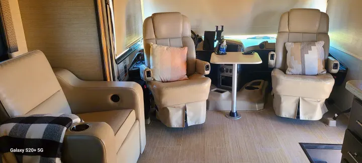 Step inside this inviting RV rental: a spacious cabin featuring comfy captain's chairs with pillows and a small table.. Entegra Coach Vision XL 2020
