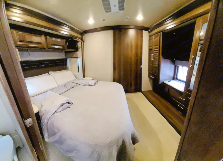 Cozy RV rental bedroom features a comfortable bed, built-in cabinetry, TV, and window for a relaxing getaway.. Entegra Coach Vision XL 2020