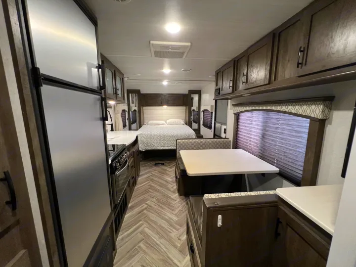 Explore this cozy RV rental interior: bedroom, full kitchen, and dinette area with ample storage. Ready for travel!. Forest River Evo 2020