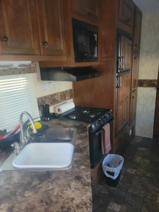 RV rental kitchen with ample wood cabinets, microwave, oven/stove, sink, and fridge for comfortable travel.. Forest River Coachmen 2012