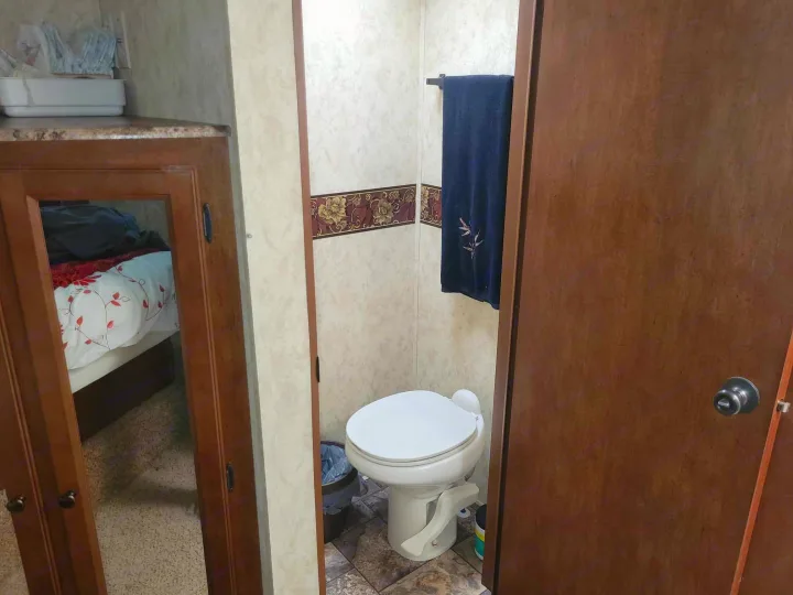 Compact RV rental interior: Features a small bathroom with a toilet and a bedroom reflected in the mirrored cabinet doors.. Forest River Coachmen 2012