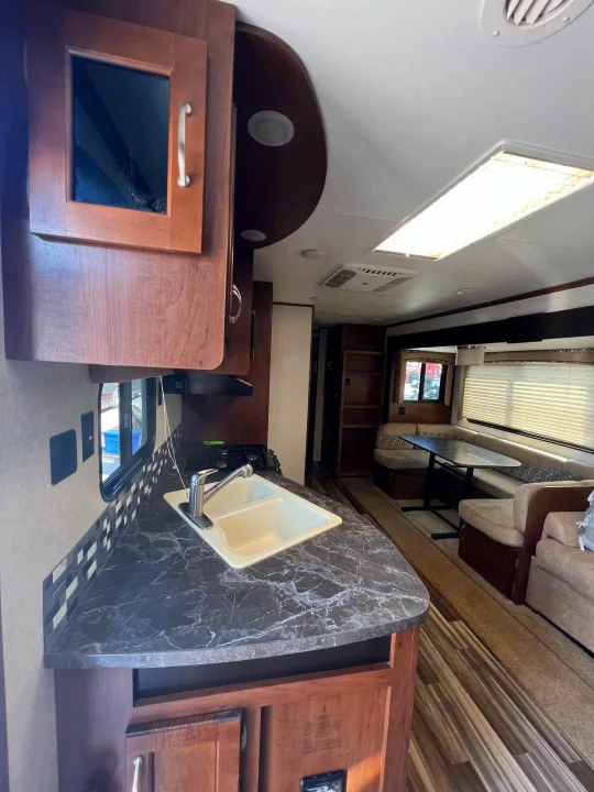 RV rental interior: clean kitchen with sink, dark countertops, and a comfortable dinette.. Jayco Jay Flight 2017