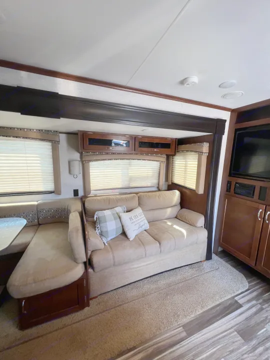 Cozy RV rental interior showing a sofa, dining booth, and entertainment area, perfect for travel comfort.. Jayco Jay Flight 2017