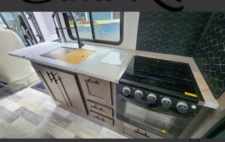 RV rental kitchen features: marble-look counter, sink, pull-down faucet, gas stove/oven, geometric backsplash, wood cabinets.. FR3 FR3 Motorhome 2023