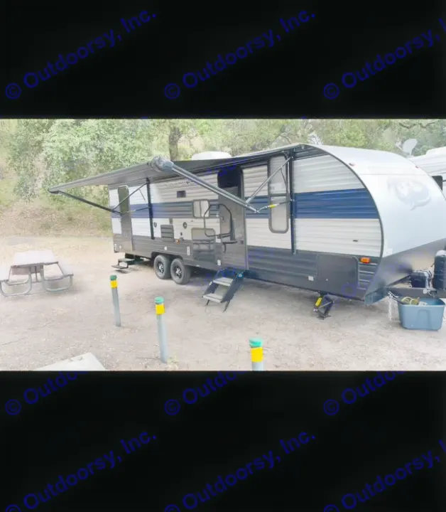 This RV rental is parked at a campsite, with its awning extended and a picnic table nearby. Ready for your trip!. Forest River Cherokee Grey Wolf 2021
