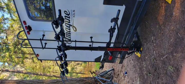 Back of an RV rental featuring a Yakima bike rack, with a bicycle on the ground. Perfect for a cycling and camping trip.. Grand Design Imagine XLS 2021