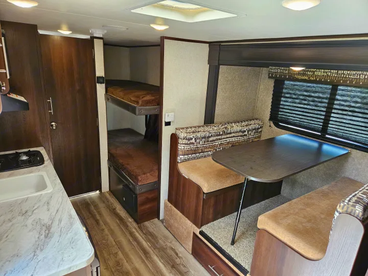 Compact RV rental interior: kitchen, dinette with patterned seating, and bunk beds. Ideal for your next adventure.. Jayco Jay Flight SLX 2019