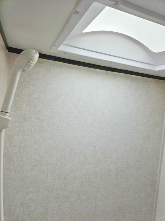 RV rental shower interior with a compact shower head and skylight, showing textured, light gray walls.. Jayco Jay Flight SLX 2019