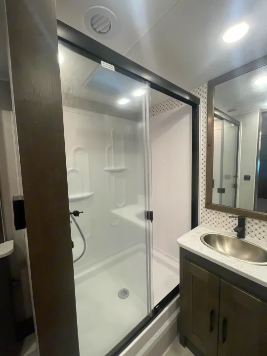 Sleek RV rental bathroom: glass shower, white molded interior, vanity with sink, and mirror with tiled backsplash.. Coachmen MIRADA 35ESF 2026