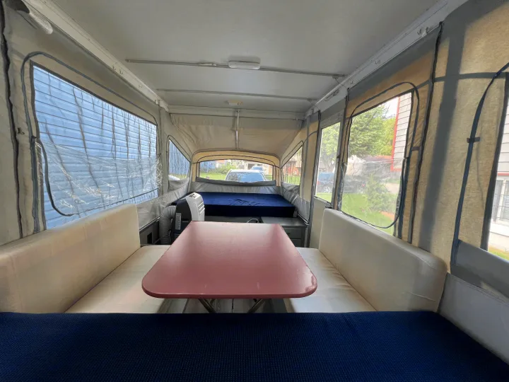 Inside this pop-up camper RV rental, a dining area, bed, and bright windows offer a comfortable camping experience.. Coleman Destiny Cedar 1992