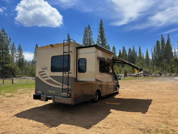 This RV rental is perfectly set up at a scenic forest campsite, with its slide-out and awning extended for outdoor comfort.. Winnebago Fuse 2017