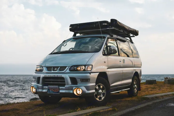 Silver Mitsubishi Delica van, equipped for off-road adventure, parked by the ocean. Perfect for an RV rental getaway.. Mitsubishi Delica 2005