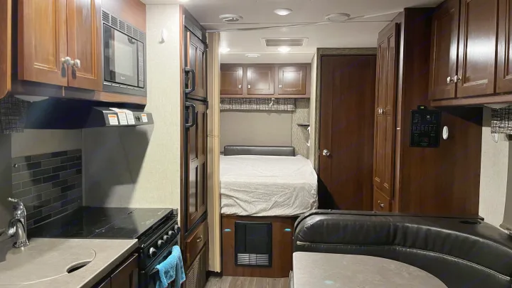 A compact yet complete RV rental interior, showcasing kitchen appliances, bed, and dining bench for versatile travel.. Forest River Sunseeker 2017