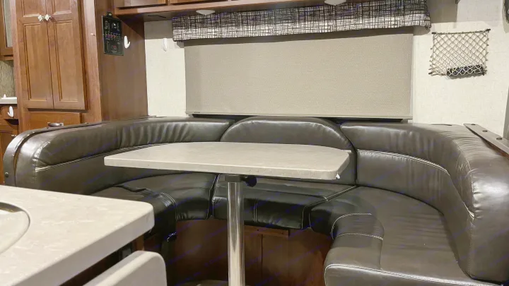 Cozy RV rental dinette with dark upholstered booth seating & light table, perfect for dining or lounging.. Forest River Sunseeker 2017
