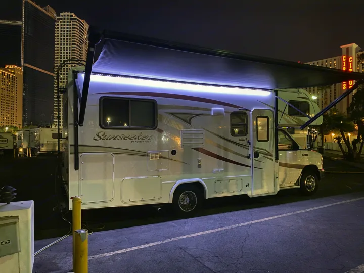 Brightly lit rv rental, a Sunseeker motorhome, parked at night with city buildings and a 'Circus' sign in background.. Forest River Sunseeker 2017