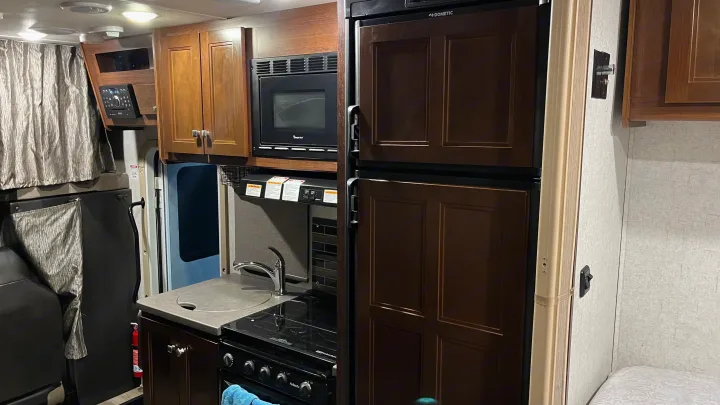 Explore this RV rental's well-equipped kitchen with microwave, fridge, and entertainment system for travel comfort.. Forest River Sunseeker 2017