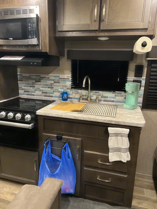 This RV rental kitchen features a full setup: microwave, stove, sink, coffee maker, and storage, ready for your trip.. Jayco Jay Flight SLX 2021